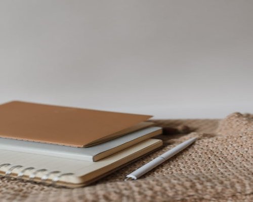 A detailed close up of an open journal notebook stacked over a table next to clean drinking water glasses