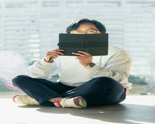 A person sitting comfortably holding a modern electronic tablet at eye level avoiding neck strain